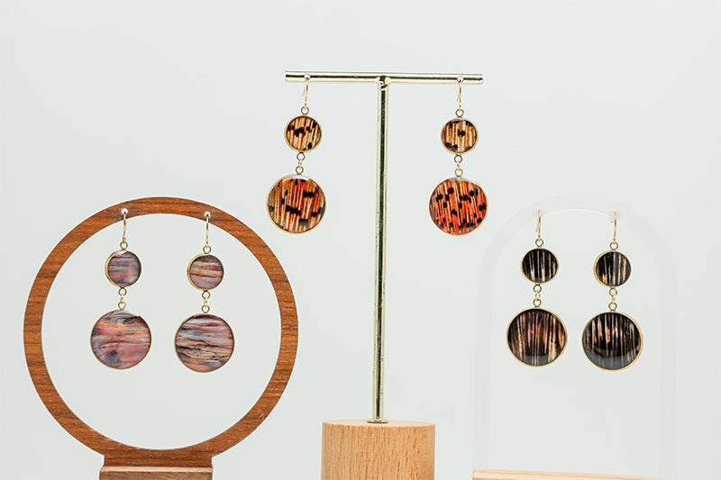 Three Dual Lionfish Gold Dangles on stands on a white background. 