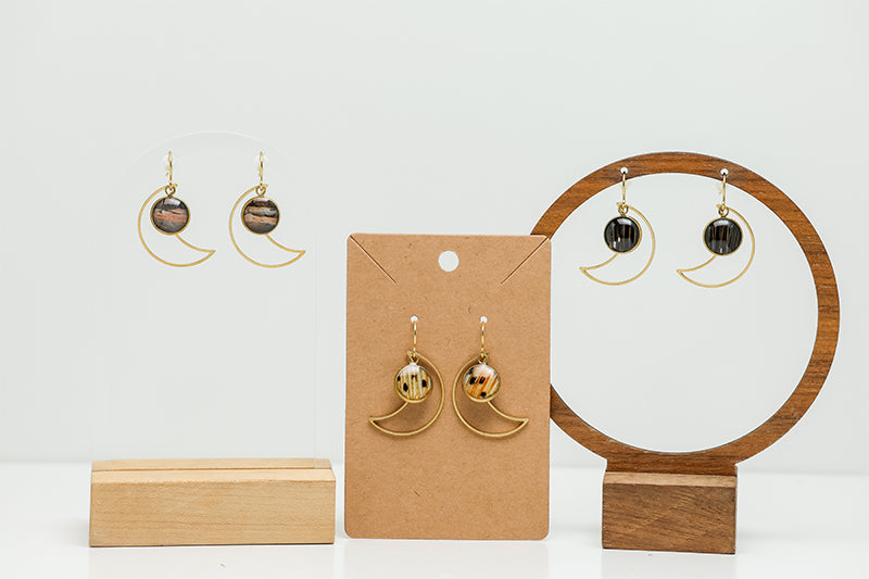 Three Golden Moon Earrings on stands on a white background. 