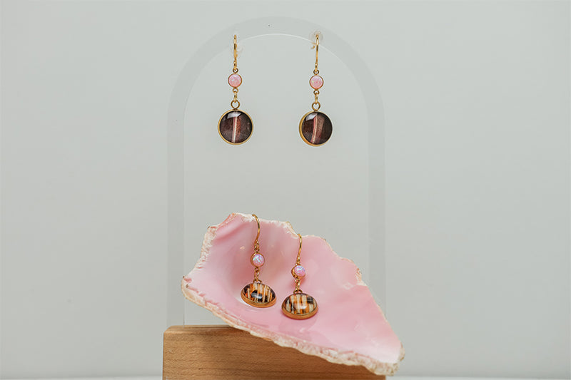 two Seashell Pink Opal Earrings on a white background with a pink shell at the bottom of the image. One pair is in the shell. 