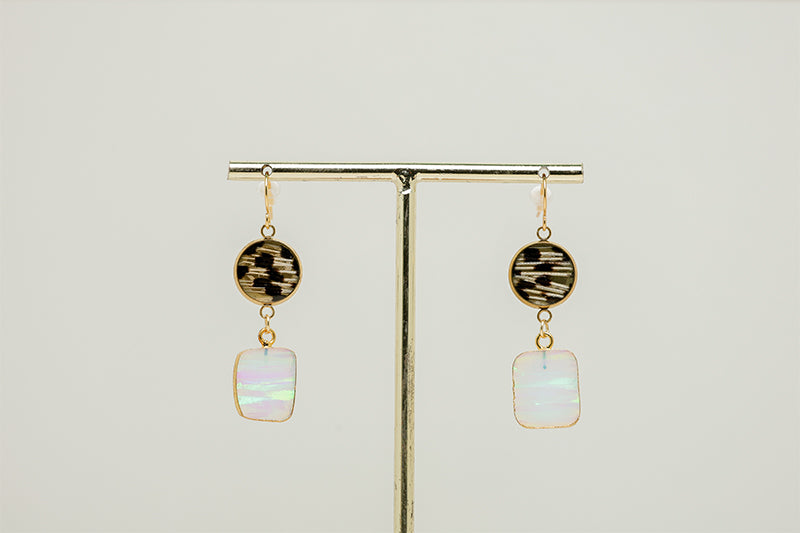 A pair of Opal Slice Earrings on a gold rod stand on a white background. 