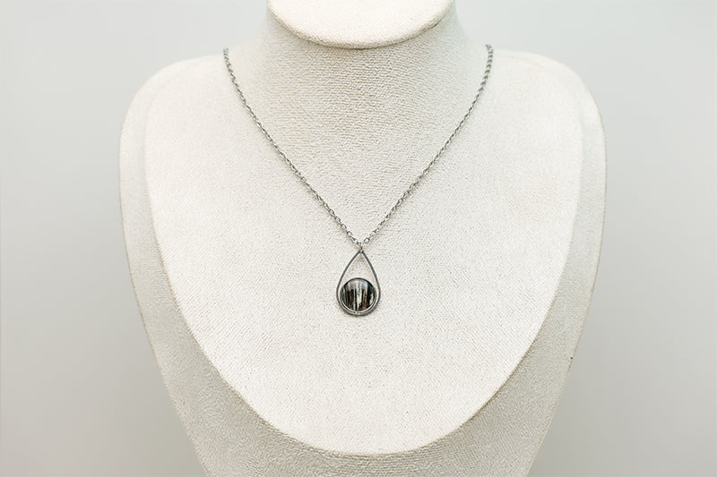 A Teardrop Necklace on a cream necklace display bust. 