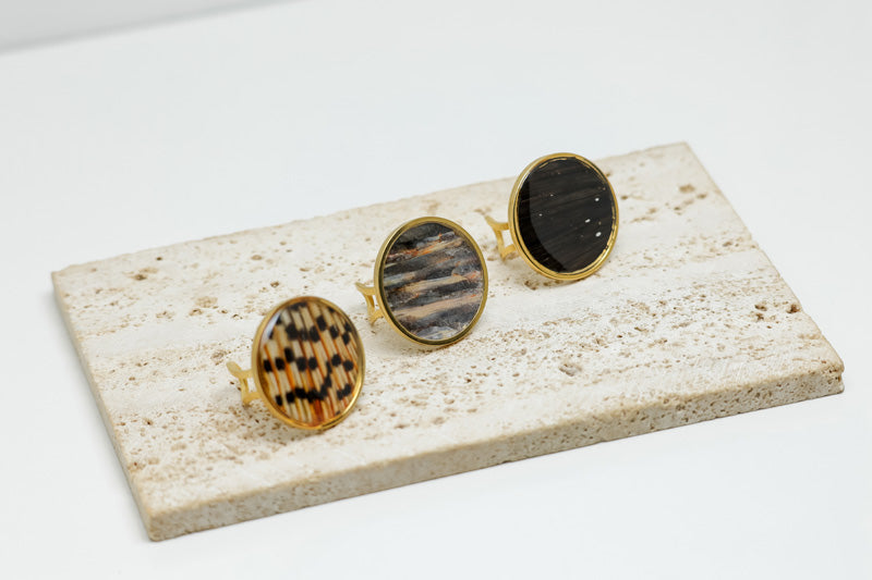 Three Gold Statement Rings on white marble on a white background.