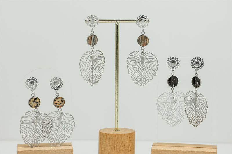 Three pairs of Monstera Leaf Mandala Drops on stands on a white background. 