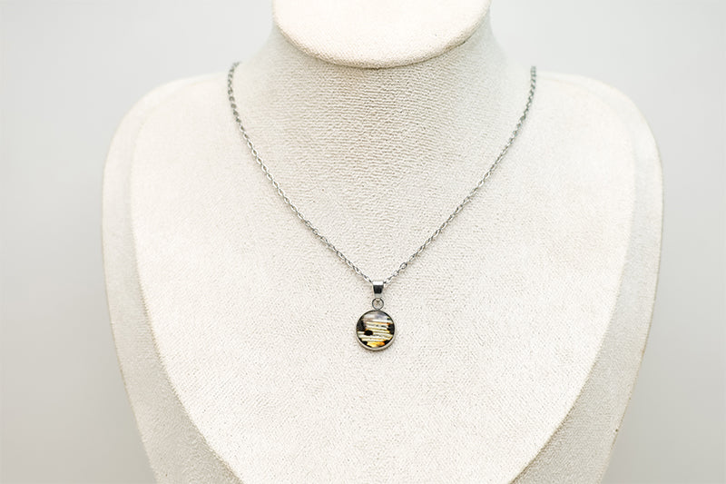A Small Silver Necklace on a cream necklace display bust. 