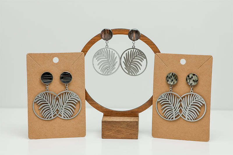 Three pairs of Tropical Palm Earrings on stands on a white background. 