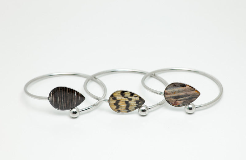 Three silver Teardrop Cuffs on a white background. 