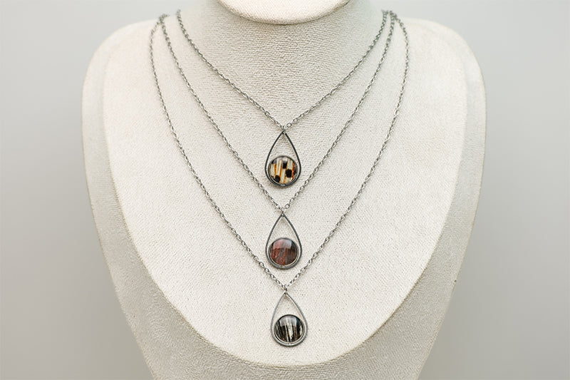 Three Teardrop Necklaces on a cream necklace display bust. 