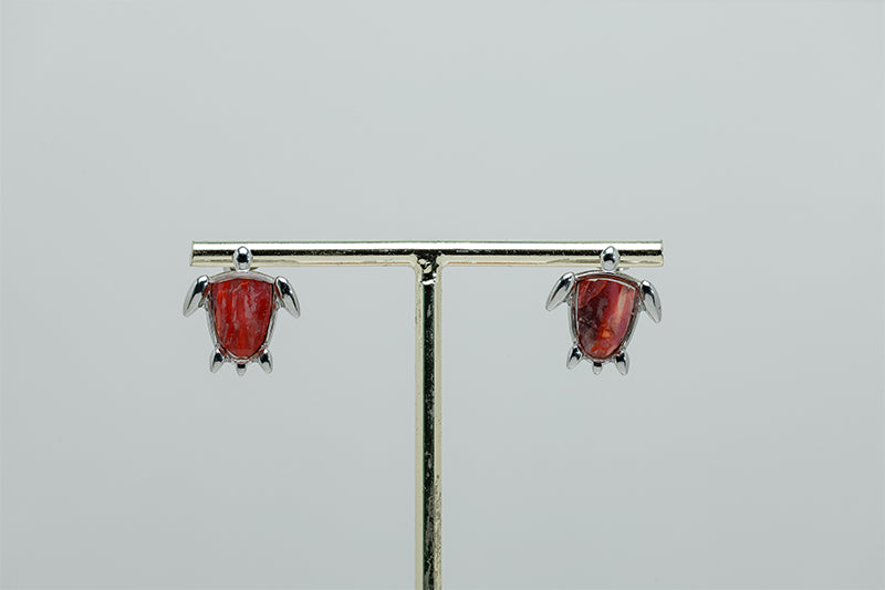 Mini Silver Turtle earrings on a stand on a white background.
