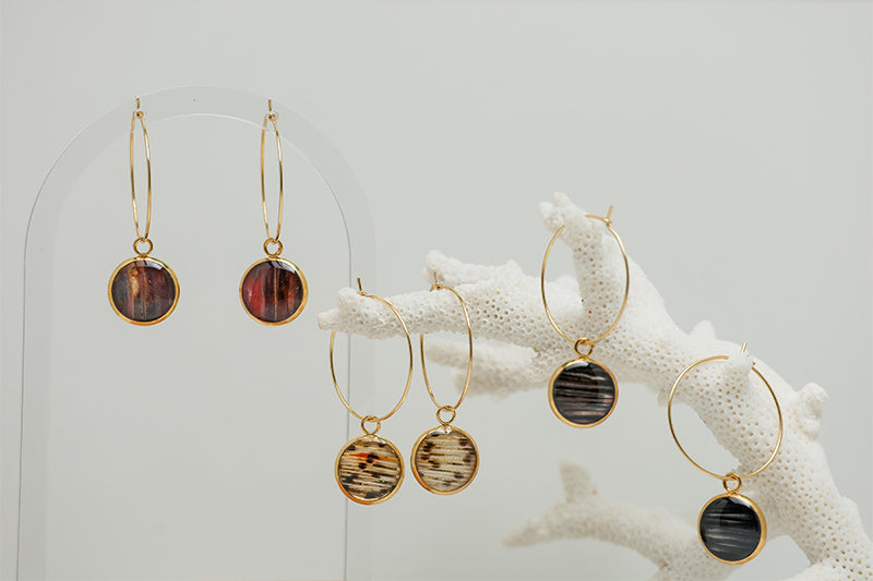 Three pairs of Gold Hoops earrings on white coral on a white background.