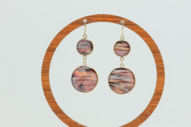 Dual Lionfish Gold Dangles on a wooden circular earring stand on a white background.  