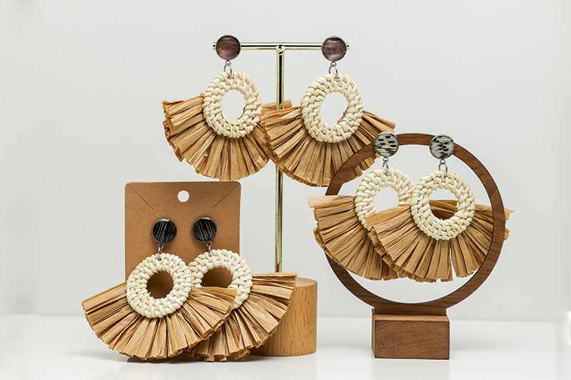 Three pairs of Boho Rattan Statement Earrings on stands on a white background.  