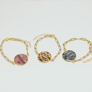 Three gold chain bracelets with different lionfish fins pendants on a light gray background