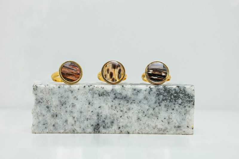 Three Gold Adjustable Rings on black and white marble on a white background.