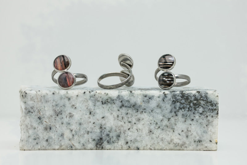 Three Silver Double Pendant Adjustable Rings on black and white marble on a white background.