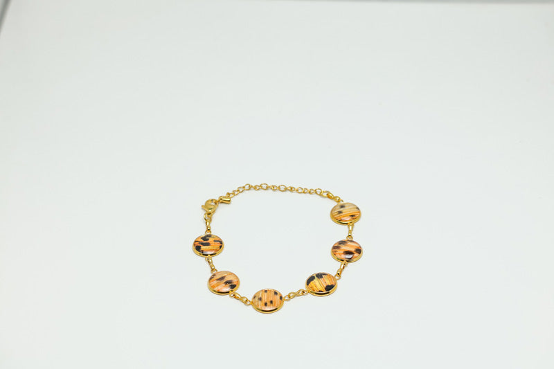 A Gold Tennis Bracelet with six tailfin charms on a white background.