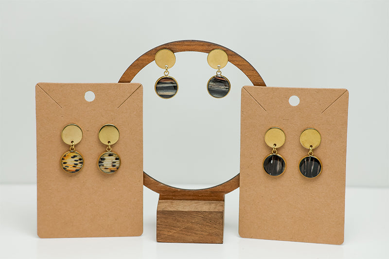 Three pairs of Round Golden Earrings on stands on a white background.  