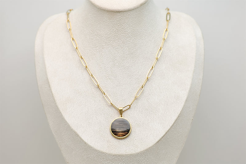 A Large Gold Necklace on a cream necklace display bust.